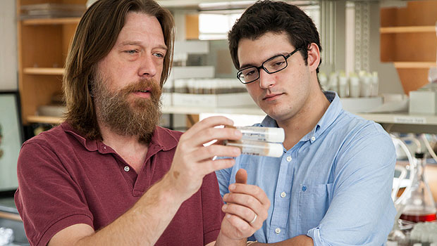 Erik Johnson examines test tubes with graduate student Jason Braco.