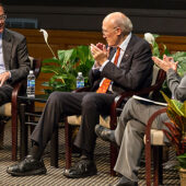 Alan Simpson and professor Katy Harriger applaud a point by Erskine Bowles (left).