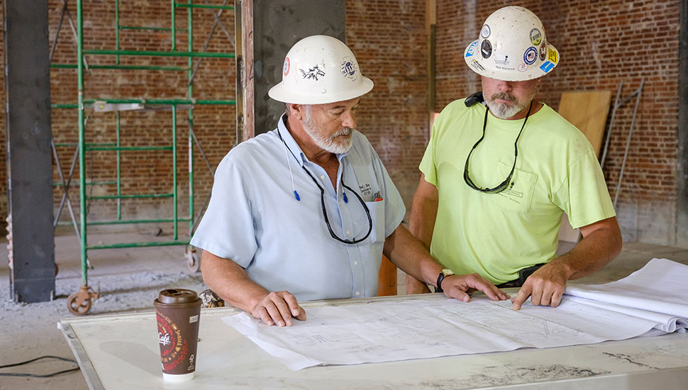 Jim Parham (left), superintendent on the Reynolds Gym transformation project, looks at blueprints.