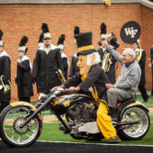 Arnold Palmer on a motorcycle with the Demon Deacon