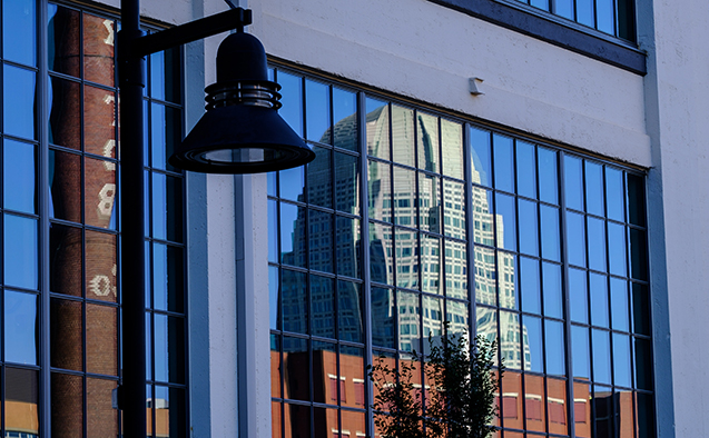 The Winston-Salem skyline reflected in a window of the Wake Downtown building