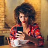 Worried woman looks at her cell phone.