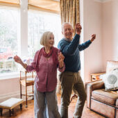 An older couple dances in their home.