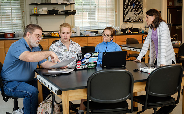 Wake Forest biology professors Dan Johnson and Sabrina Setaro talk with graduate students Noah Bressman and Jenny Howard about new methods for grading science writing, in a lab in Winston Hall.