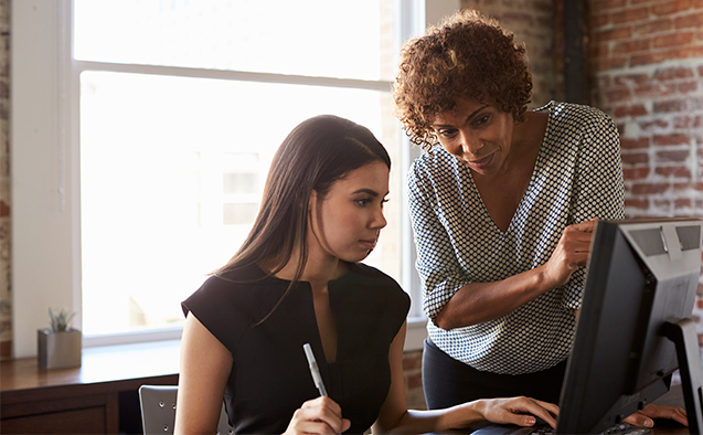 Two Businesswomen Working On Computer In Offic