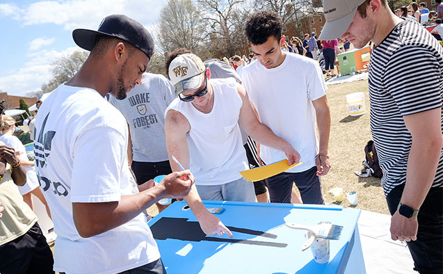 Students at WFU paint desks for students from a local elementary school