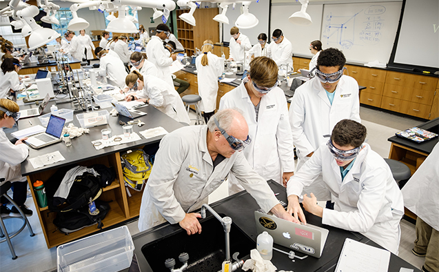 Professor Al Rives works with students on a general chemistry lab procedure.