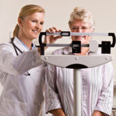 Doctor weighing senior woman - Stock image