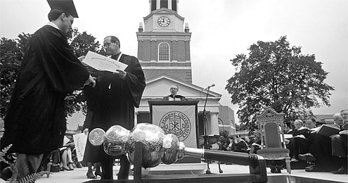 Thomas Hearn presents a diploma in front of Wait Chapel.