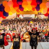 Students dance on stage in front of a large crowd