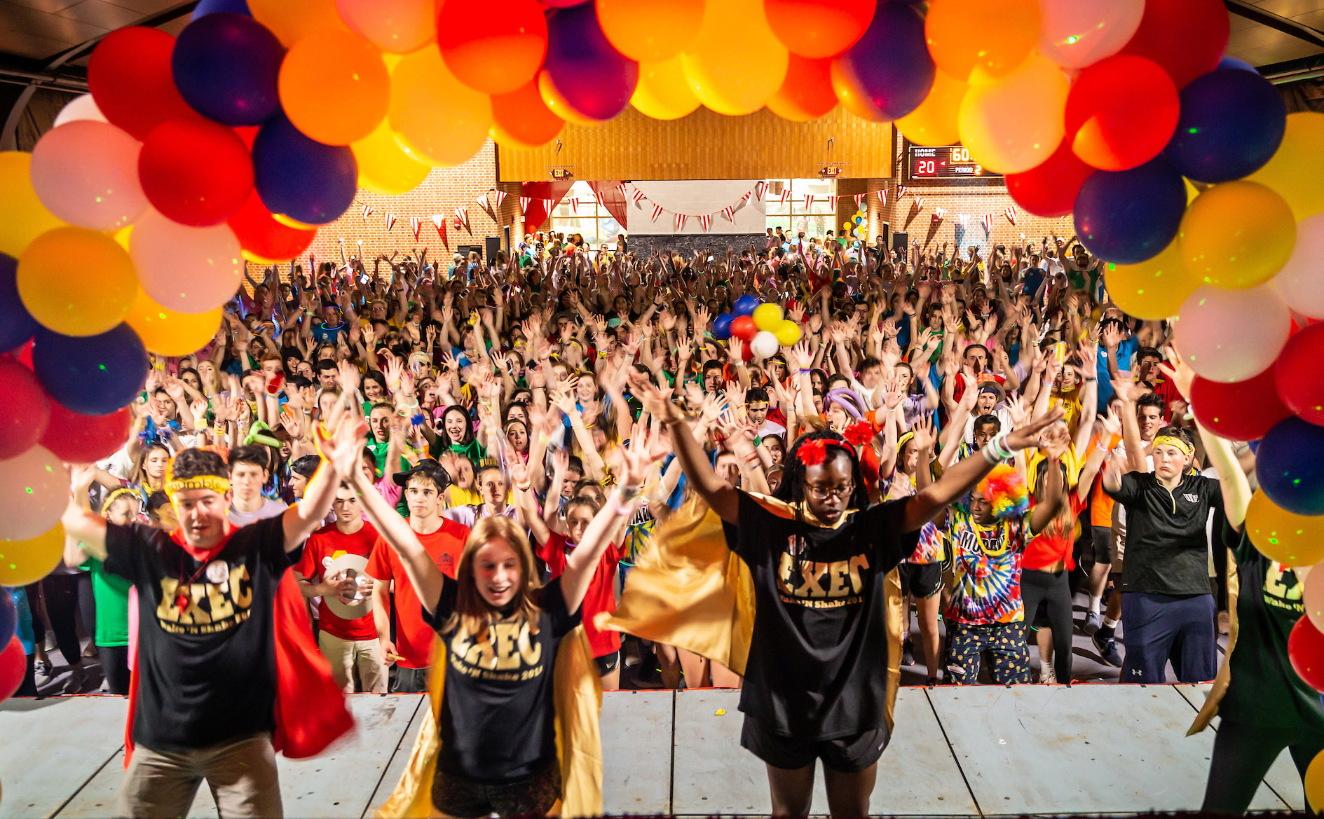 Students dance on stage in front of a large crowd