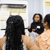 Student presenting poster at research day.