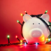 Piggy bank with holiday lights draped around it.