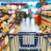 empty grocery cart in aisle at grocery store