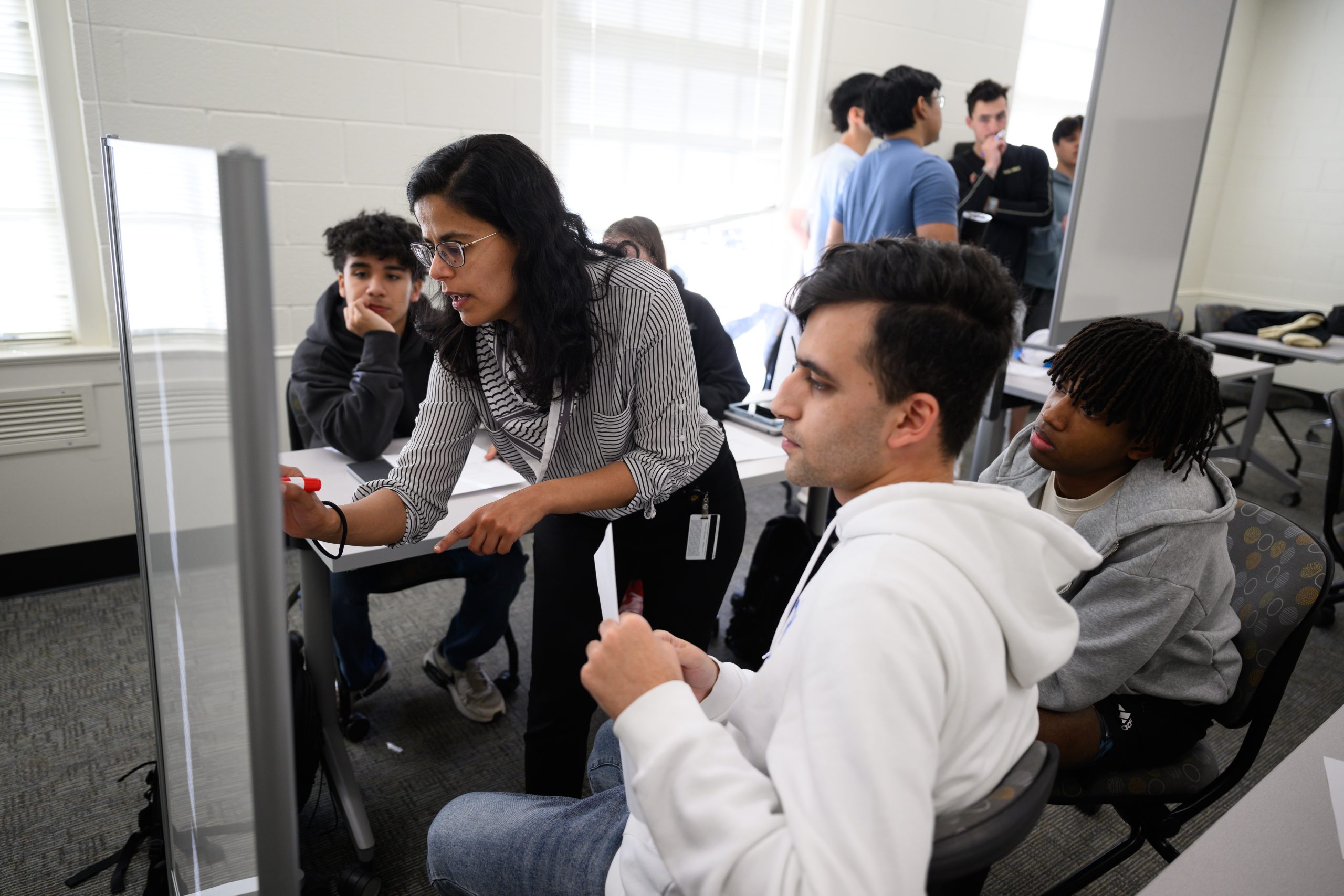 Wake Forest University Computer Science Prof. Sarra Alqahtani teaches her Fundamentals of Computer Science class in Manchester Hall on Friday, February 7, 2025.    Prof. Sarra Alqahtani helps Catherine Neely (’28), Elham Fayzi (’28), Mikkel King (’27), and Eddy Picazo (’28) work through an exercise in class.