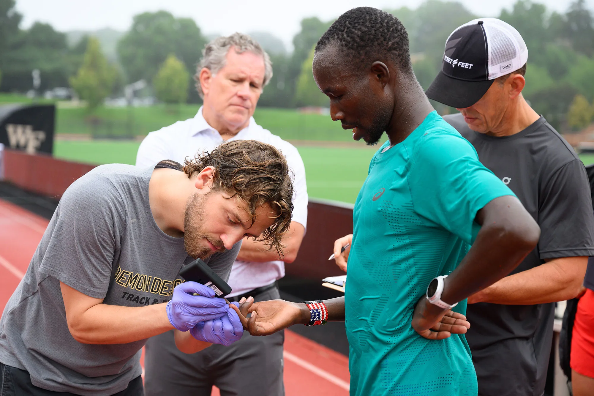 Elite marathoner John Korir (second from right) visited Wake Forest in early August for his first lactate threshold performance testing. John LePino, who coaches track and field at Wake Forest, draws blood for the test.
