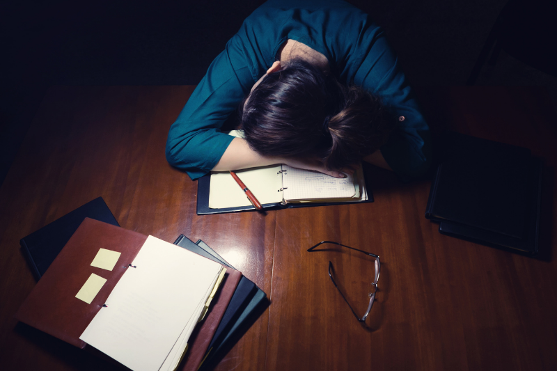 student with head on desk, overwhelmed by work.