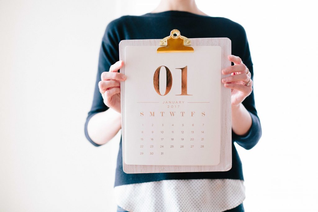 Decorative image, person holding a calendar page on a gold clipboard