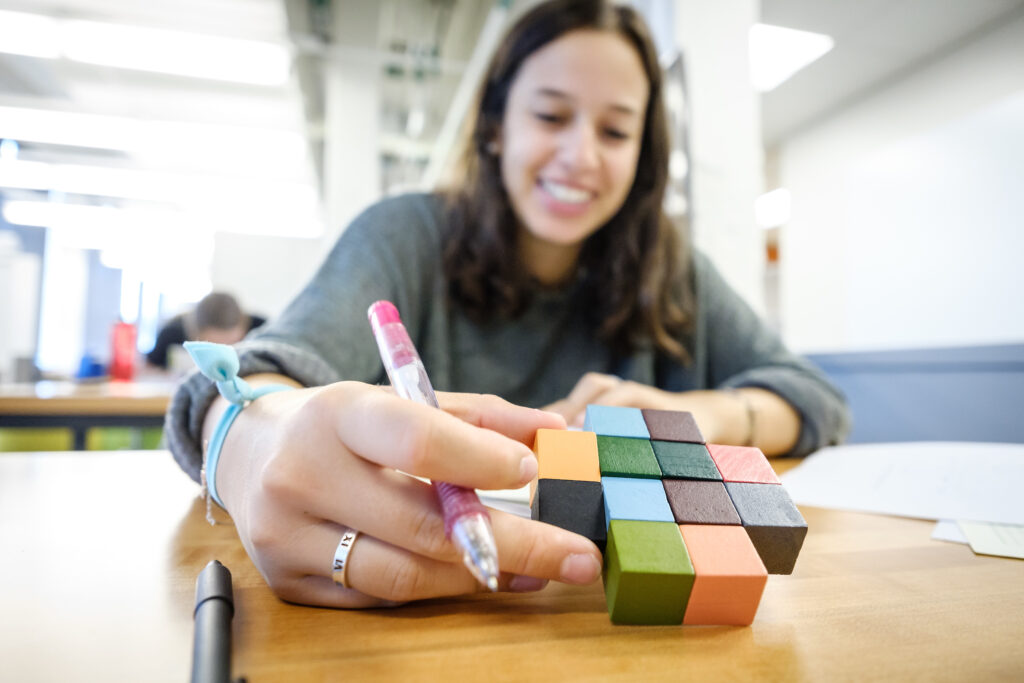 Image of a student working on an engineering assignment with a set of cubes