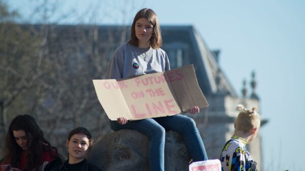 woman holding cardboard signage "our future's on the line"