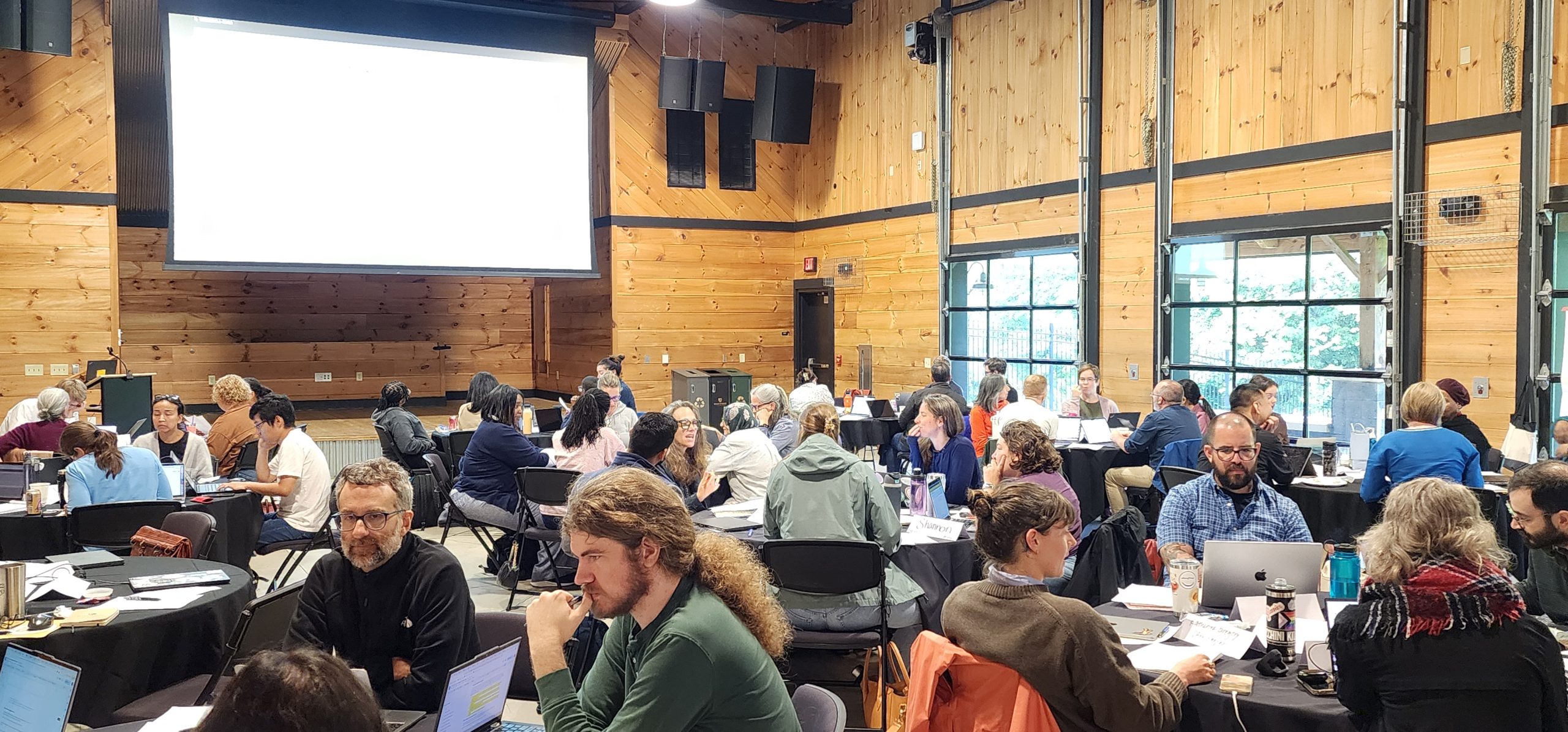 faculty sitting at round tables in groups in the University Activity Space on the Reynolda Campus