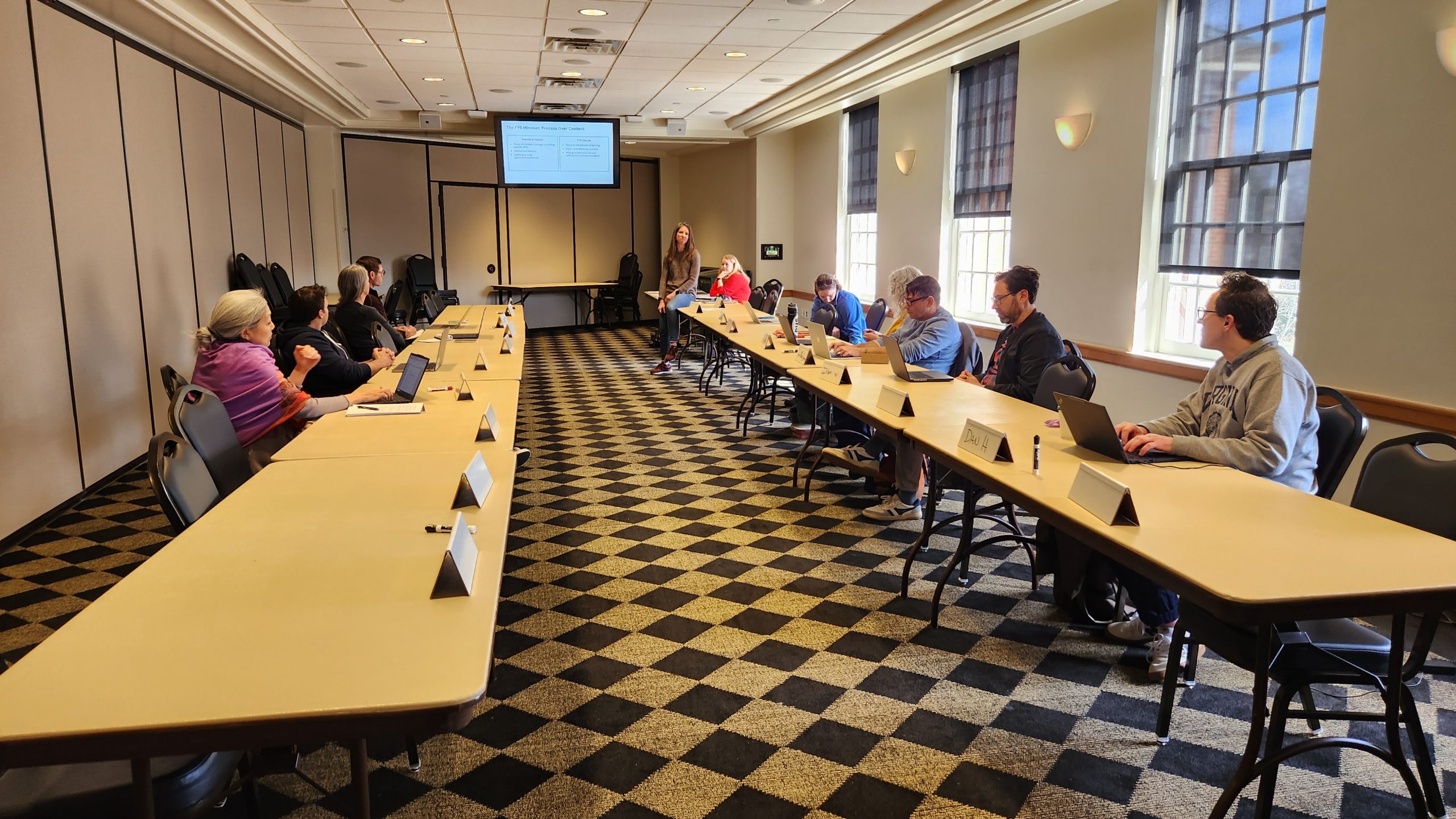 Interior Benson multipurpose room with tables set in a conference style and attendees of the Design Sprint FYS workshop listening to facilitators Kristi Verbeke and Melissa Maffeo.