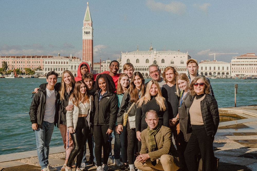 group of students stand in front of a canal