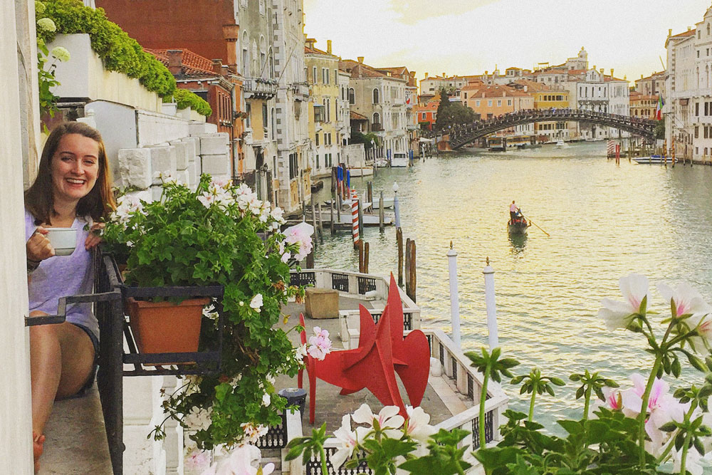 student sits on balcony overlooking canal