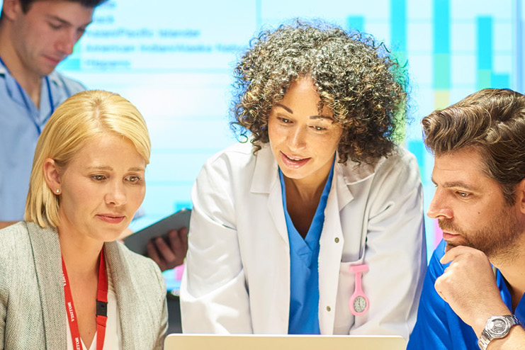 Healthcare leadership team gathered behind a computer