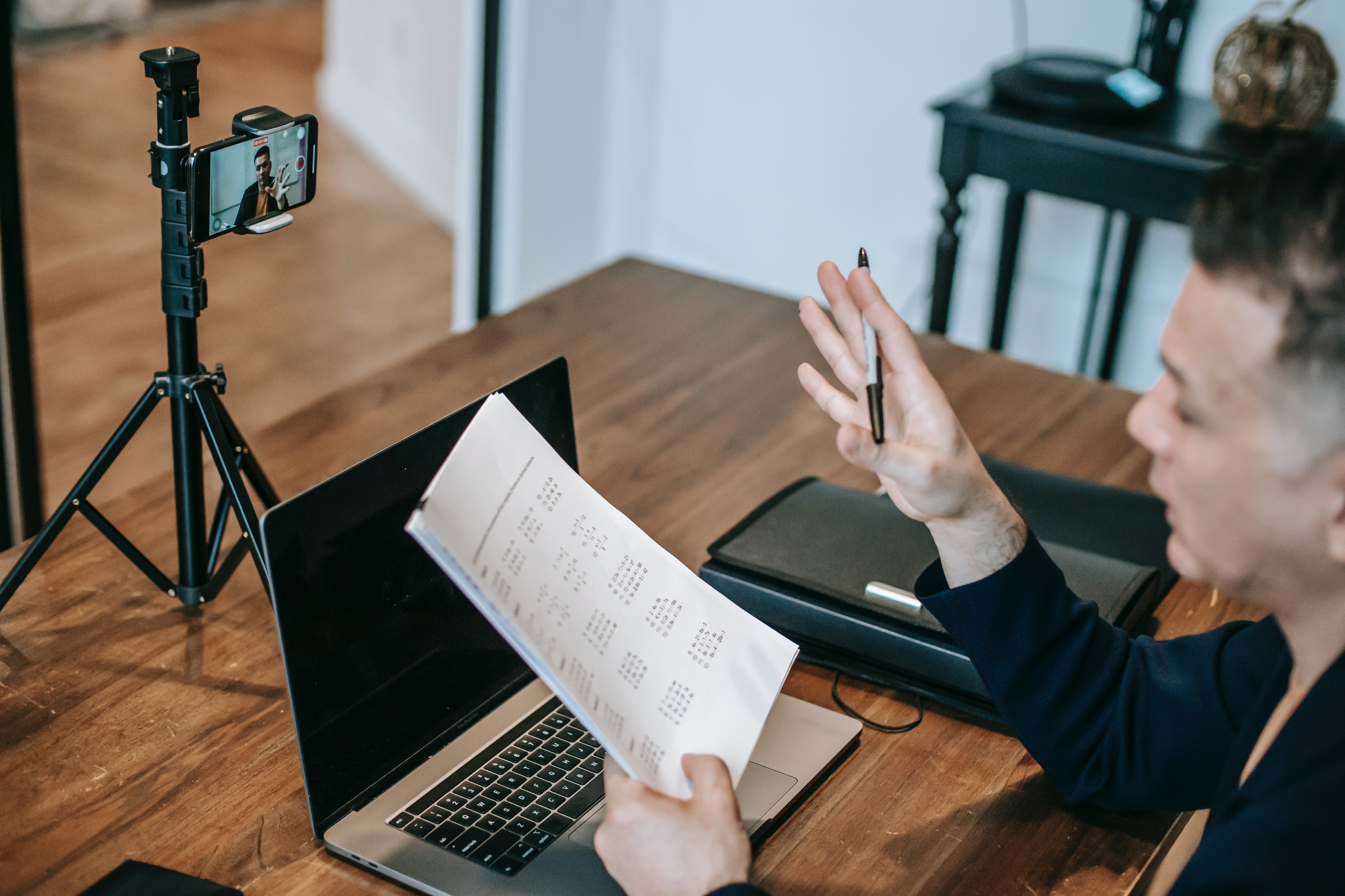 Man recording himself teaching while holding a paper