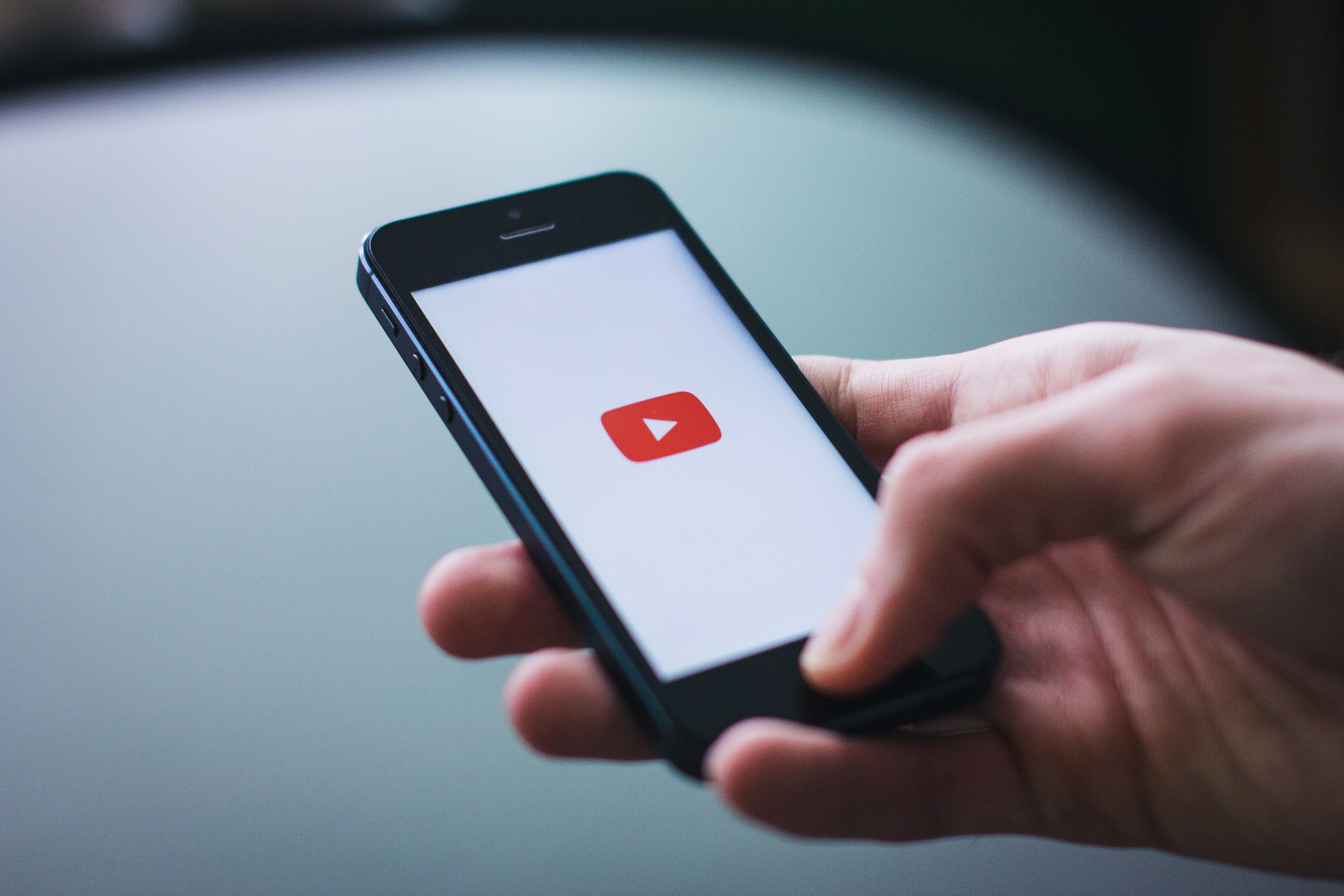 Hand holding phone that shows the Youtube Logo