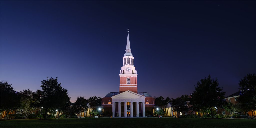 The bell tower of Wait Chapel rises over the Wake Forest campus at sunset.