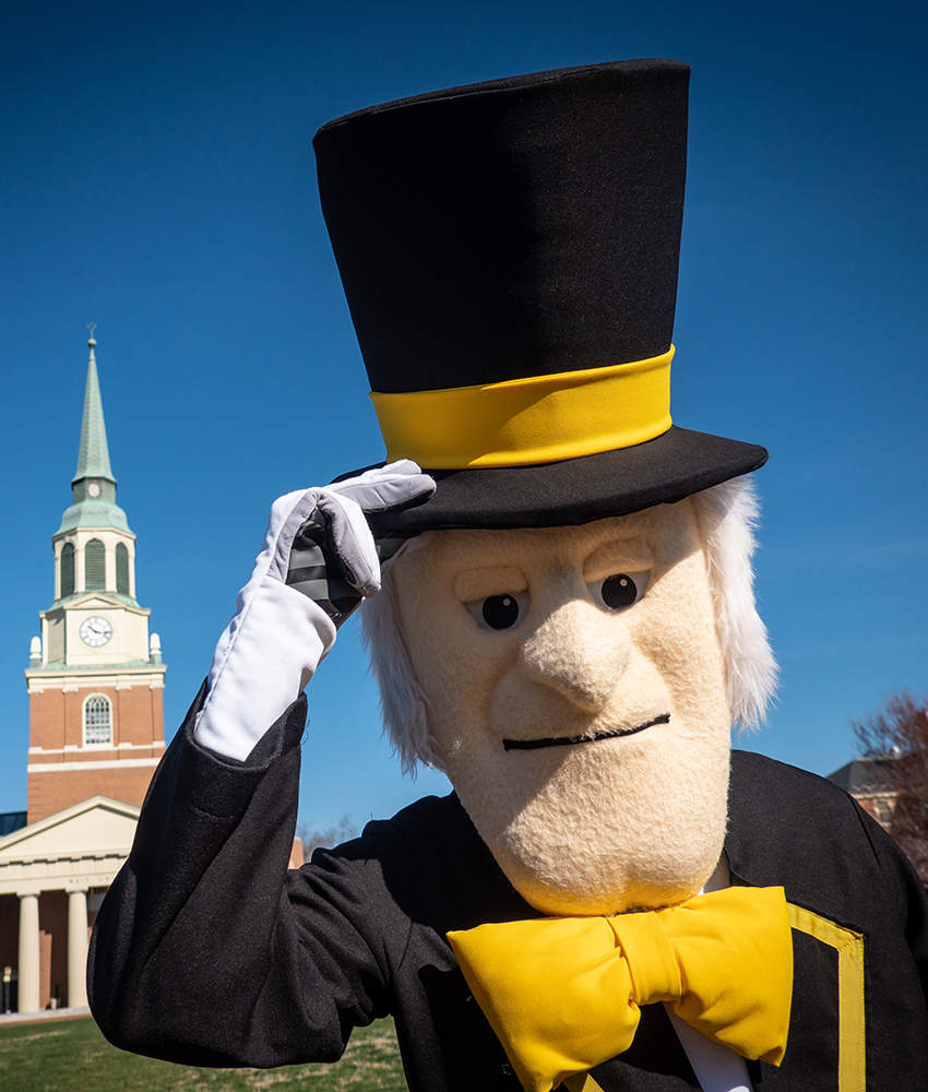 The Demon Deacon tips his hat standing in front of Wait Chapel