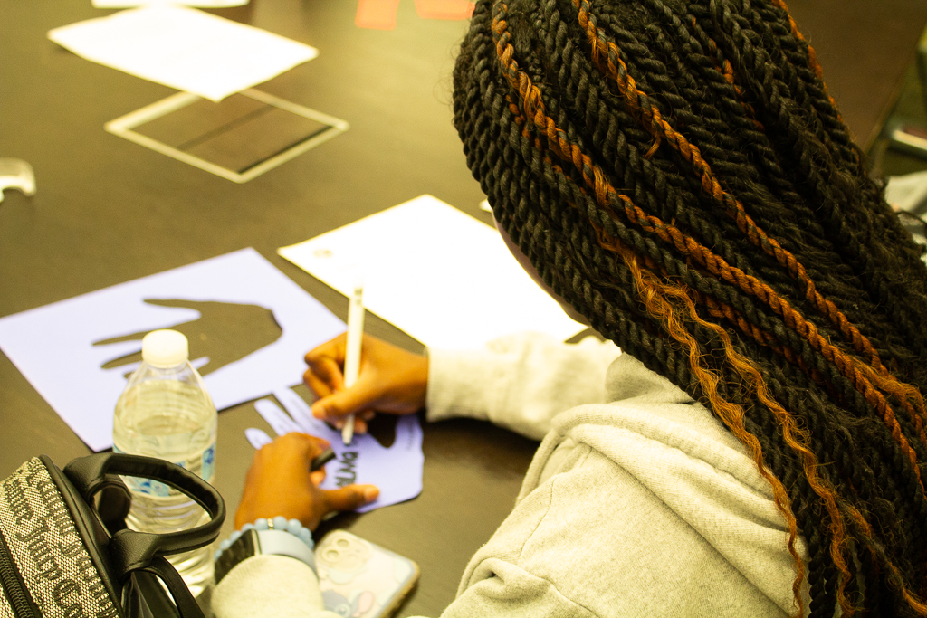 College LAUNCH Scholar creates a handprint during a Saturday Summit community building activity.