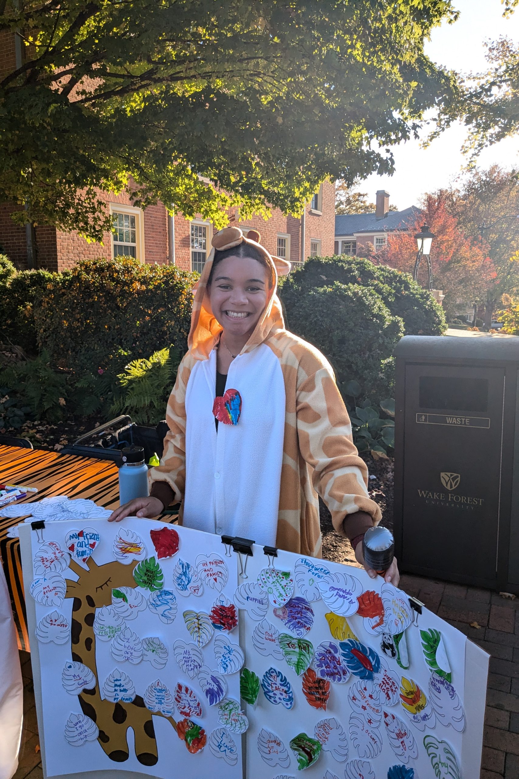 Project Pumpkin photo of a Counseling student balancing a board with paper leaves that children have written what makes them happy on.