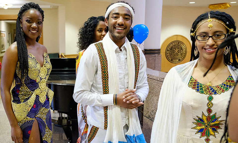Students smiling in African and Caribbean costumes at AfriCasa Night event