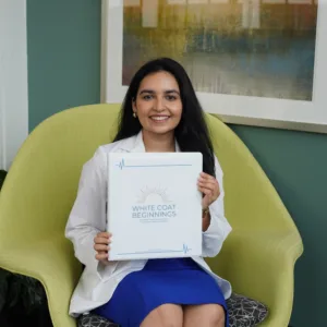 Geetika Verma ('28 MD) holding up her student guidebook White Coat Beginnings.