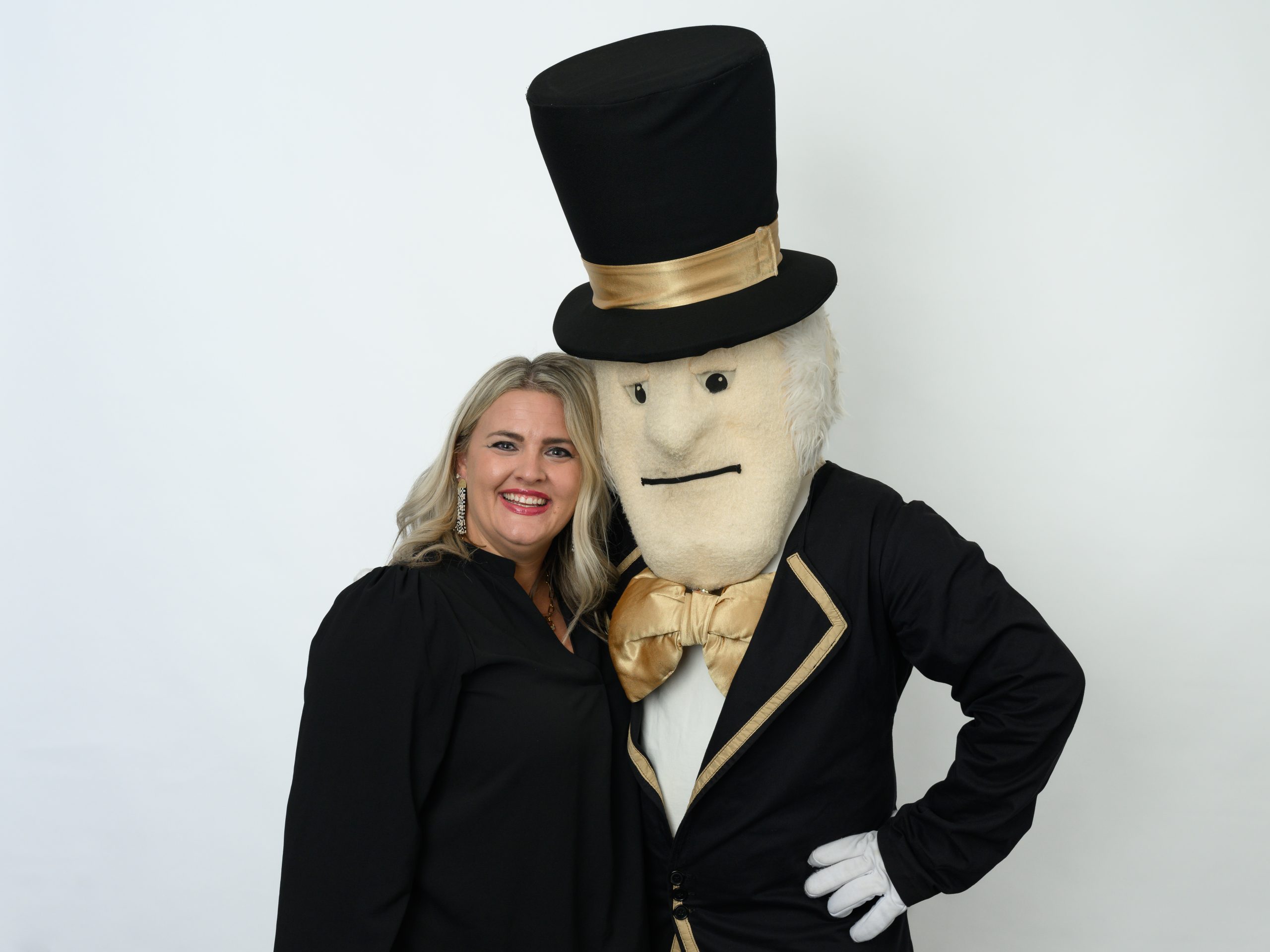 Dustie Lanier stands beside the Demon Deacon mascot smiling and giving him a side hug, while his opposite arm is propped on his hip.