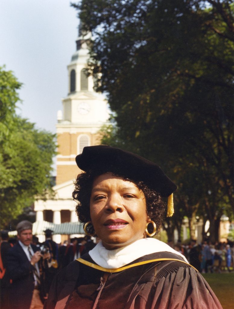 Maya Anglou stands in front of Wait Chapel wearing commencement attire