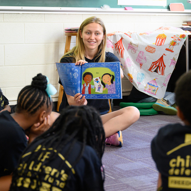 A Wake Forest student reads a picture book to local school children