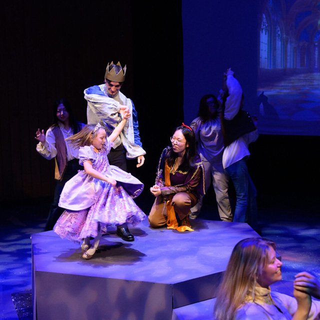 A young girl happily performs onstage with Wake Forest students