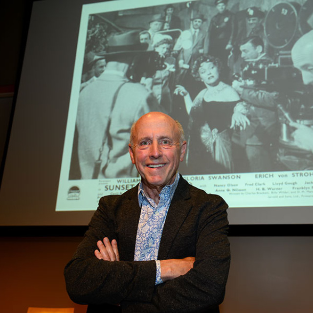 David Lubin stands in front of a still image from the film 