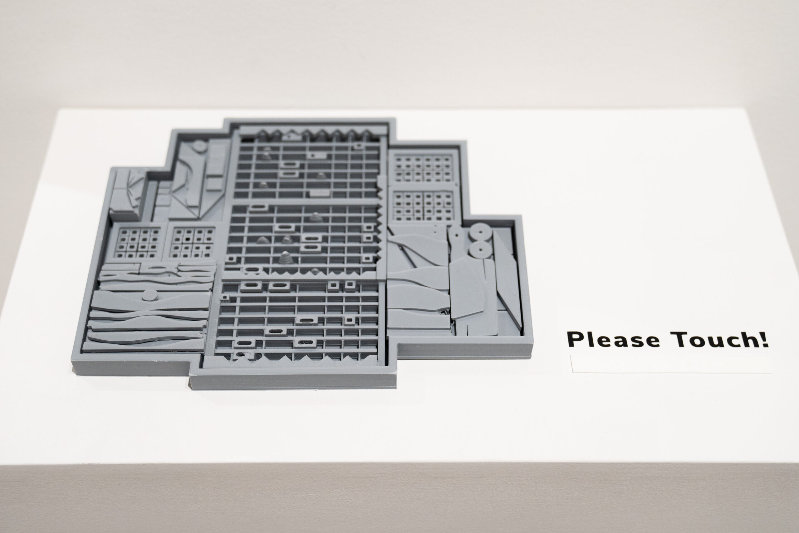 close up of a tactile art model of a Louise Nevelson sculpture on a white shelf