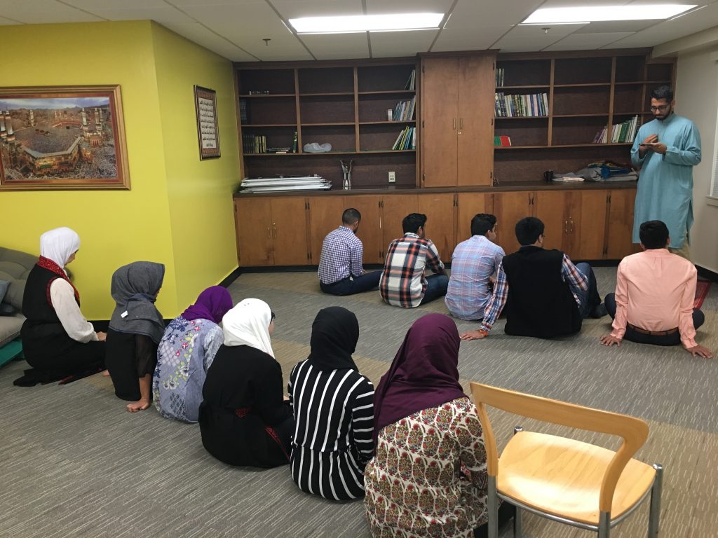 Image of Muslim Students listening to the Weekly Friday Sermon at the prayer service.