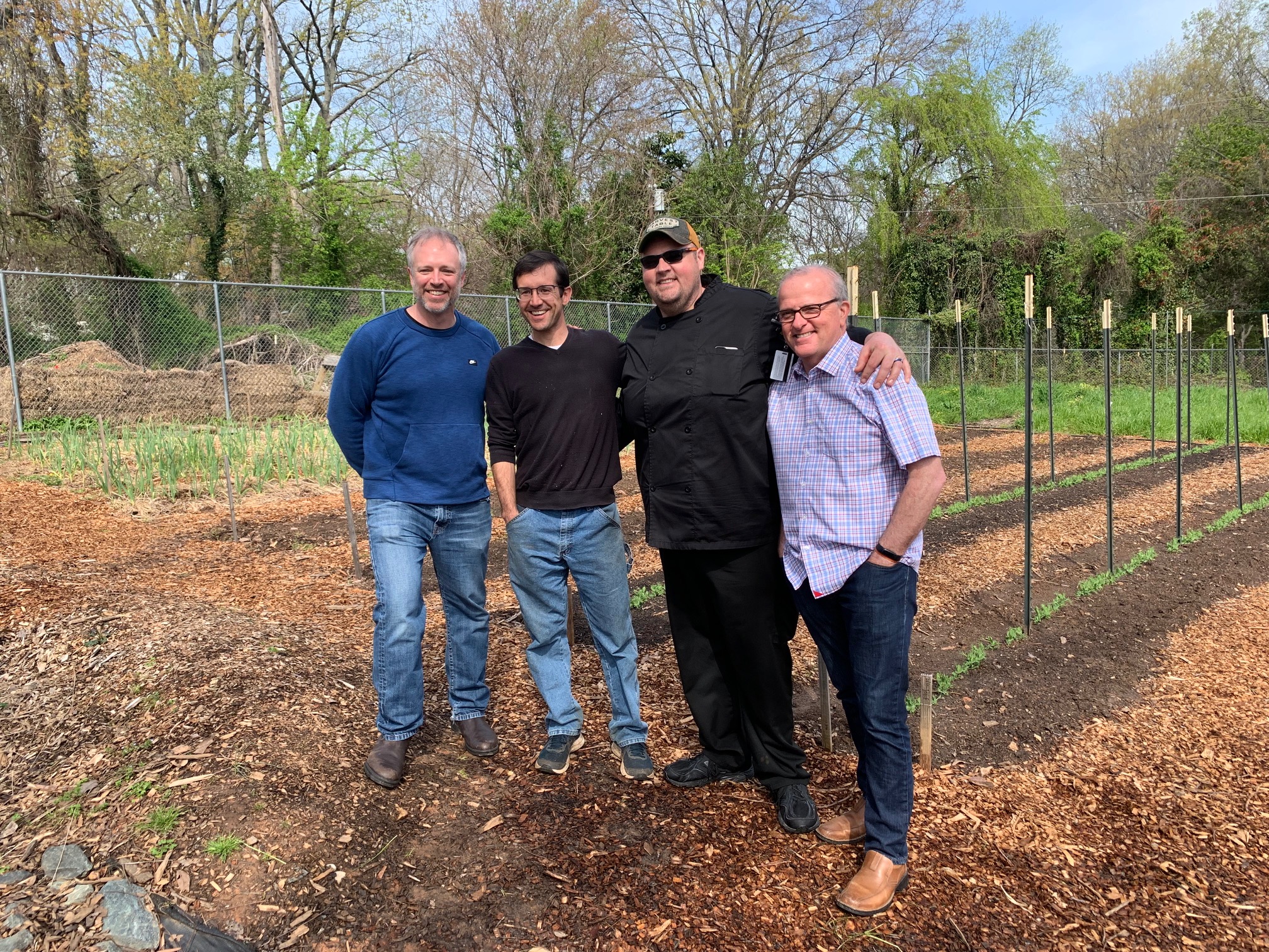A portrait of Chef Dissen, Nathan, Chef Ryan and Tim Vandeermersch standing in the Campus Garden.