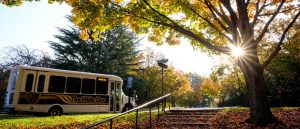 Photo of a Wake Line Shuttle passing by the sunsetting on campus  on a fall day.