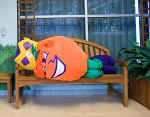 Orange mascot lies on bench