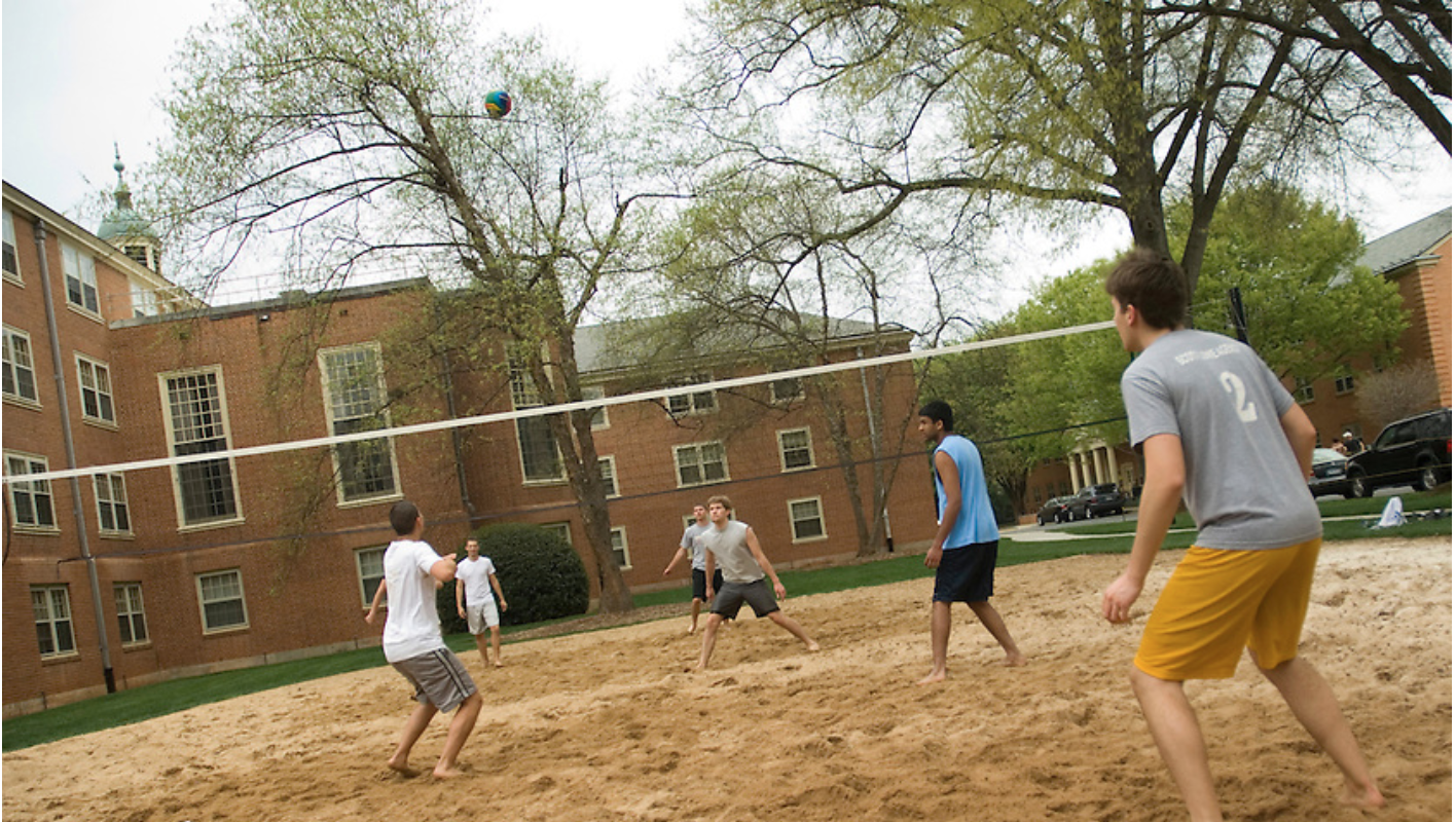 Students playing volleyball on sand courts