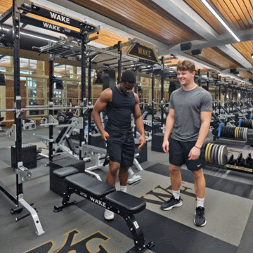 Two Wake Forest University male students in workout room. One gets an email from the Handshake system showing him jobs that he likes. He shows it to his friend and they smile.