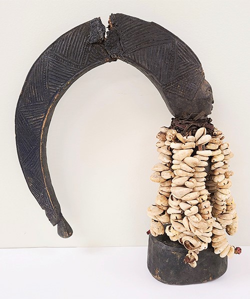 wooden Eshu figure with strings of cowrie shells